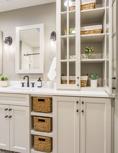 A bathroom with white cabinets and wicker baskets.