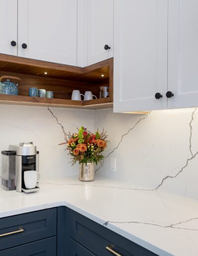 A kitchen with white cabinets and marble counter tops.