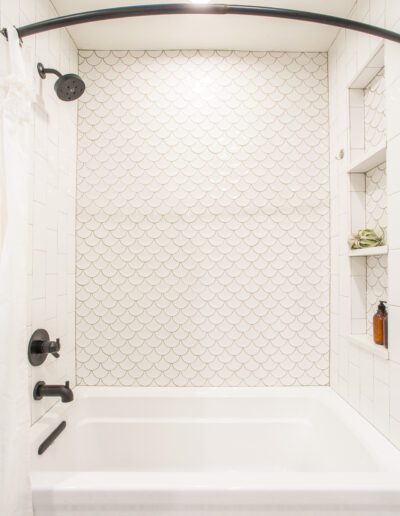 A white tiled bathroom with a tub and shower.