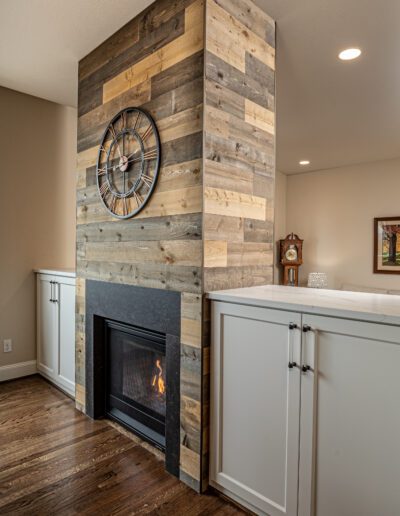 A living room with a wood fireplace and white cabinets.