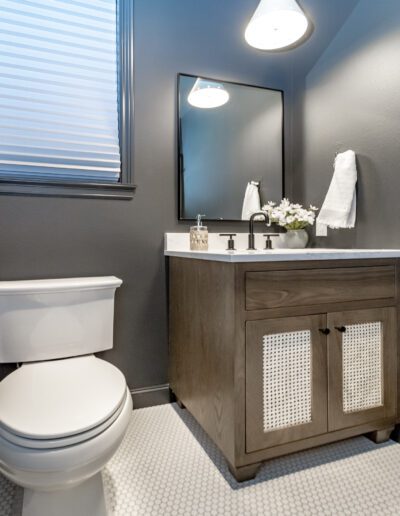 A bathroom with a toilet, sink, and mirror.