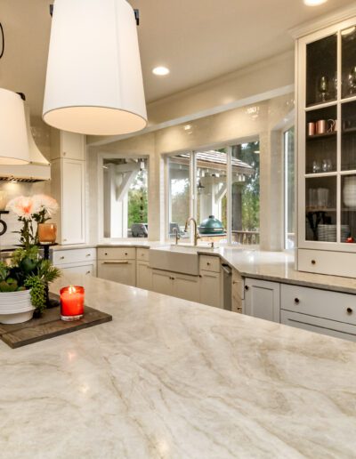 A kitchen with white cabinets and marble counter tops.