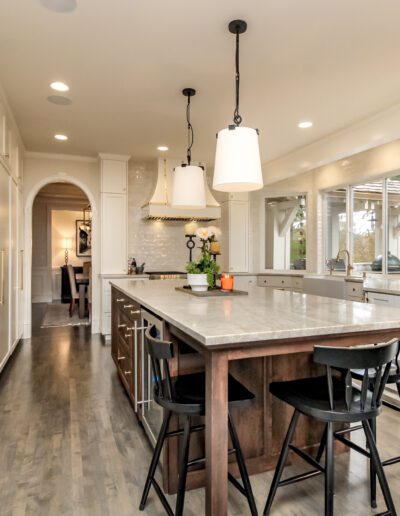 A white kitchen with a center island and black stools.