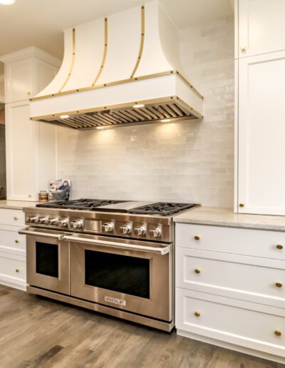 A white kitchen with a stainless steel range hood.