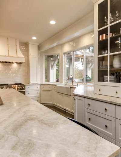 A kitchen with white cabinets and marble counter tops.