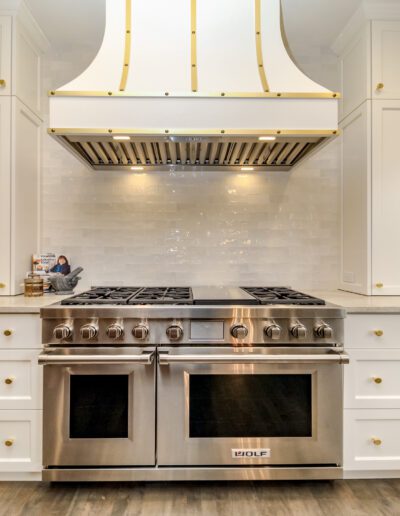 A white kitchen with a stainless steel range hood.