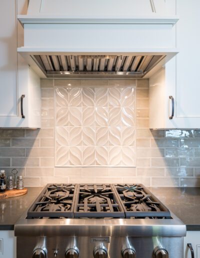 A kitchen with a stainless steel stove and white cabinets.