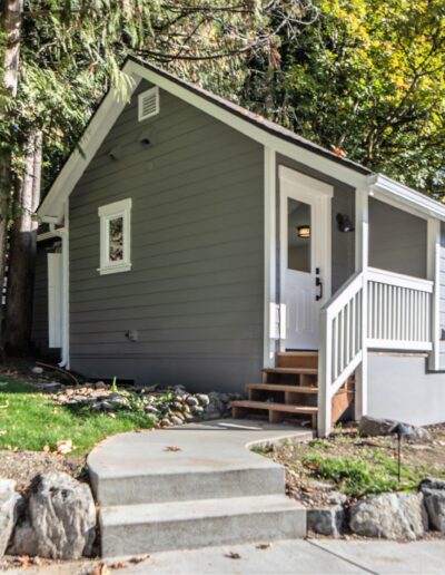 A small gray house with steps leading up to it.
