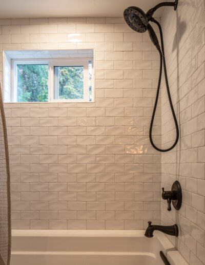 A white tiled bathroom with a black shower curtain.