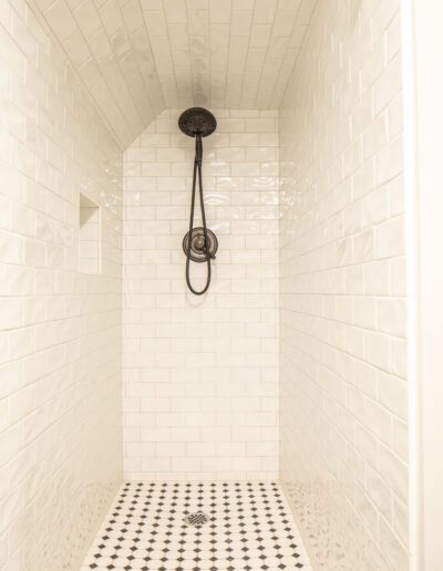 A black and white tiled shower with a shower head.