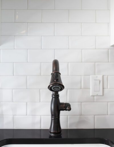 A kitchen sink with a black faucet and white tile.