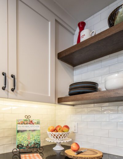 A kitchen with white cabinets and wooden shelves.