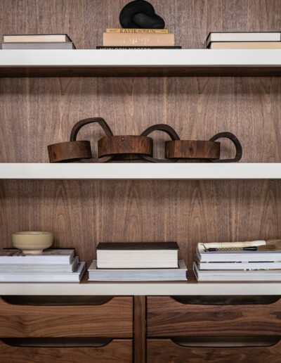 A wooden shelf with books and hats on it.