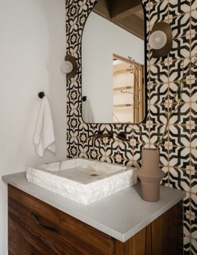 A bathroom with a black and white tiled wall.