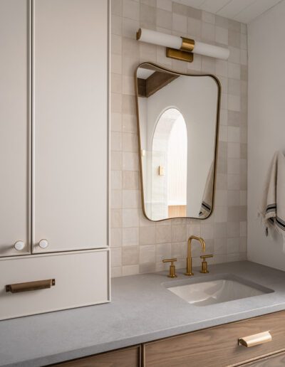 A bathroom with a white sink and gold hardware.