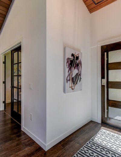 A hallway with hardwood floors and a wooden door.