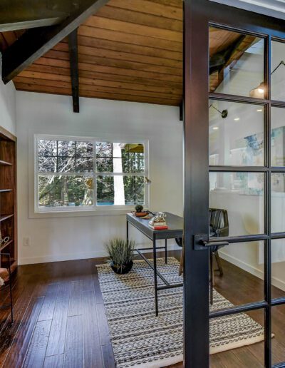 A home office with glass doors and hardwood floors.