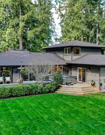 A home in the woods with a large lawn and trees.